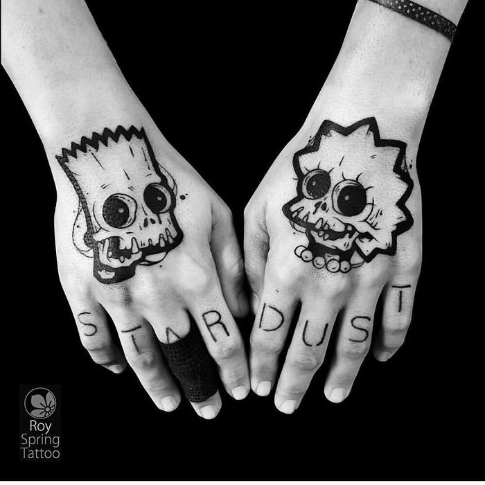 Simpsons tattoos of Bart and Lisa with skull designs on hands, featuring the word "Stardust" on fingers.