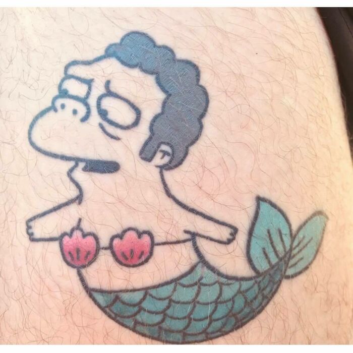 Simpsons tattoo featuring a character with a mermaid body, pink shell top, and green tail on skin.