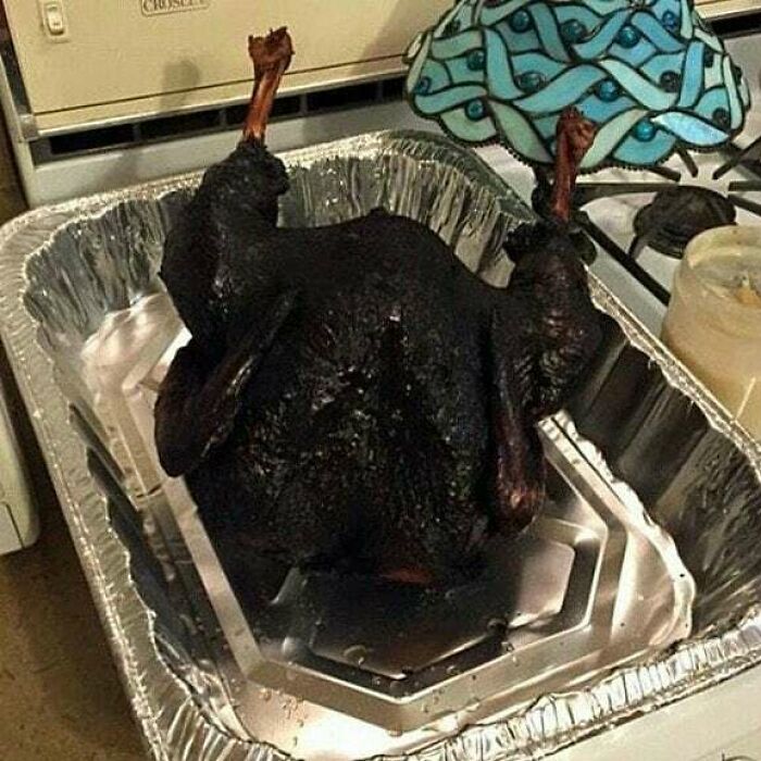 Charred turkey in a roasting pan on the stove, likely unappetizing for cooking.
