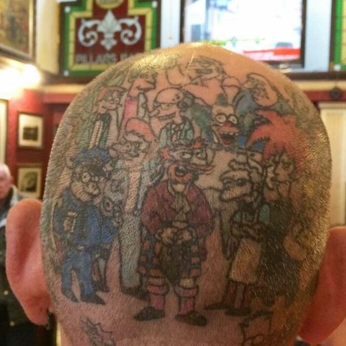 Simpsons tattoos on a shaved head, featuring various characters in a colorful design, displayed in an indoor setting.