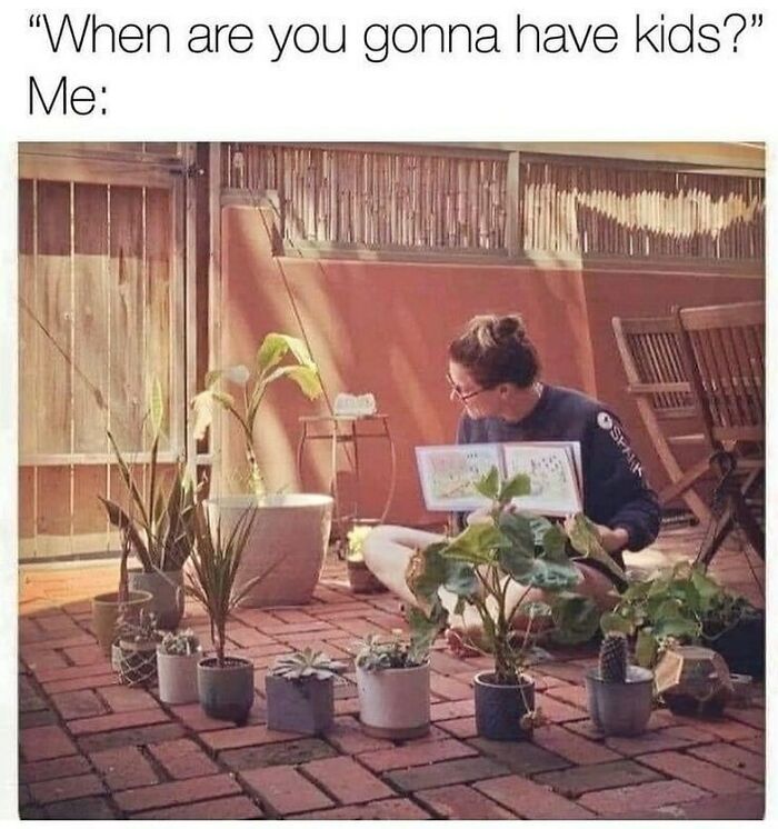 Person surrounded by potted plants, suggesting plant owners can relate to them as if they are kids.