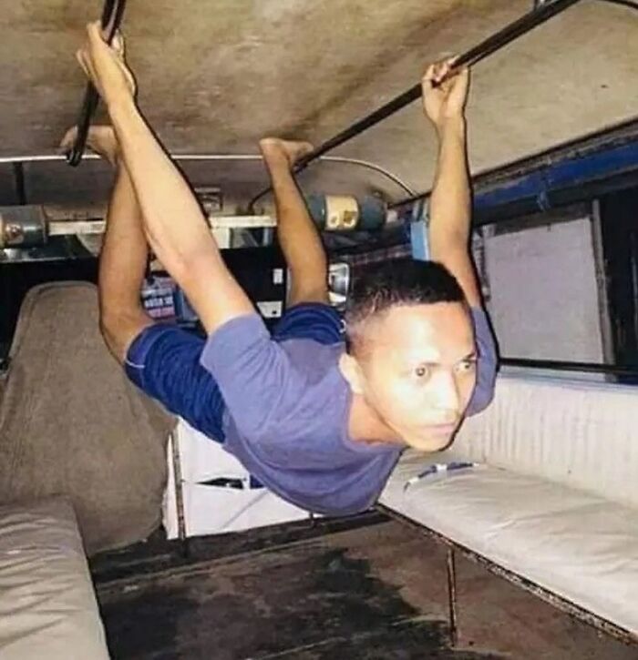 Man hanging upside down in a bus, creating a random cursed image.