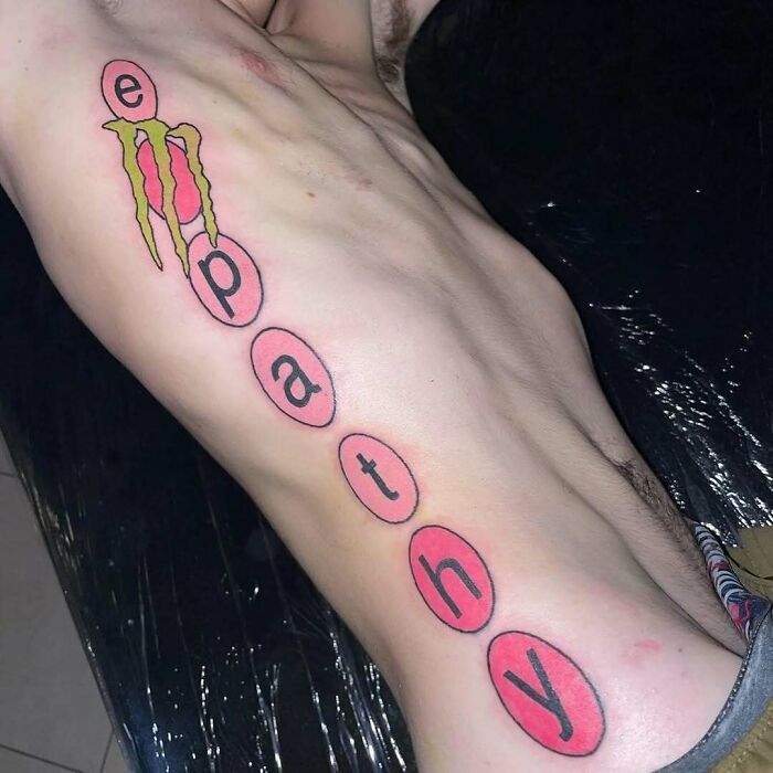 Tattoo reading "empathy" on side torso with colorful designs, exemplifying permanent mistakes.