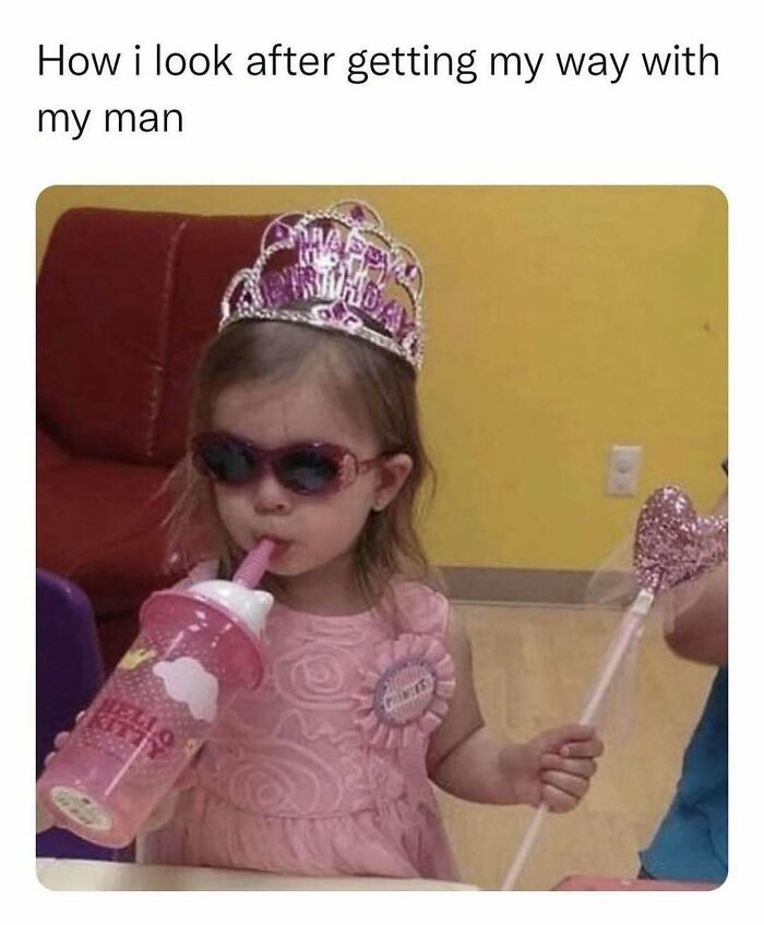 Young girl in sunglasses, sipping from a pink bottle, wearing a crown and holding a wand; a relatable meme moment.