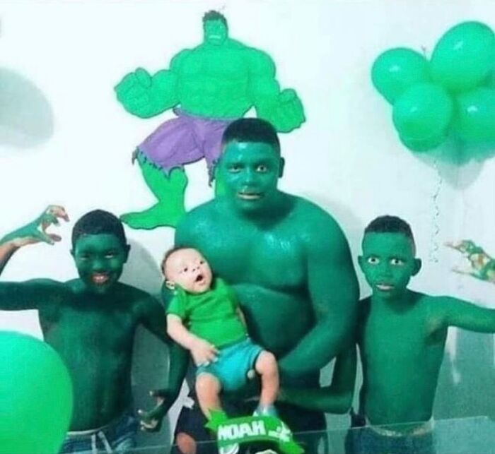 Family painted green posing for a theme party, with Hulk decorations and green balloons, embodying random cursed images.
