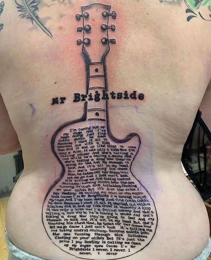 Tattoo of a guitar on back with song lyrics and "Mr Brightside," showcasing a permanent inking mistake.