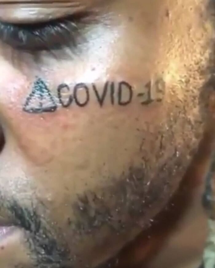 Face tattoo with "COVID-19" inked on a man's cheek, a permanent mistake.