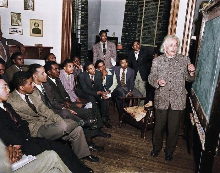 Albert Einstein teaching a group of students in a classroom captured in a vintage photo showing history up close.