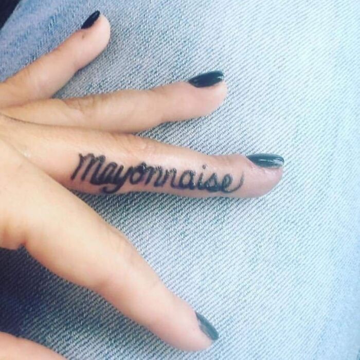 Tattoo mistake: "Mayonnaise" inked on a finger with black polished nails.