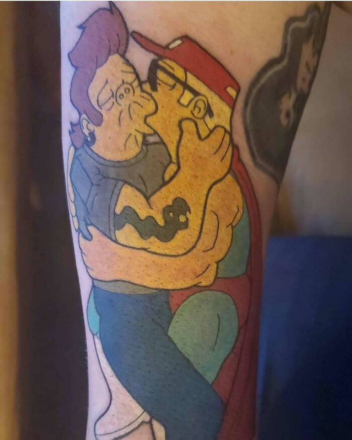 Tattoo of two Simpsons characters embracing, showcasing bold colors and a humorous vibe.