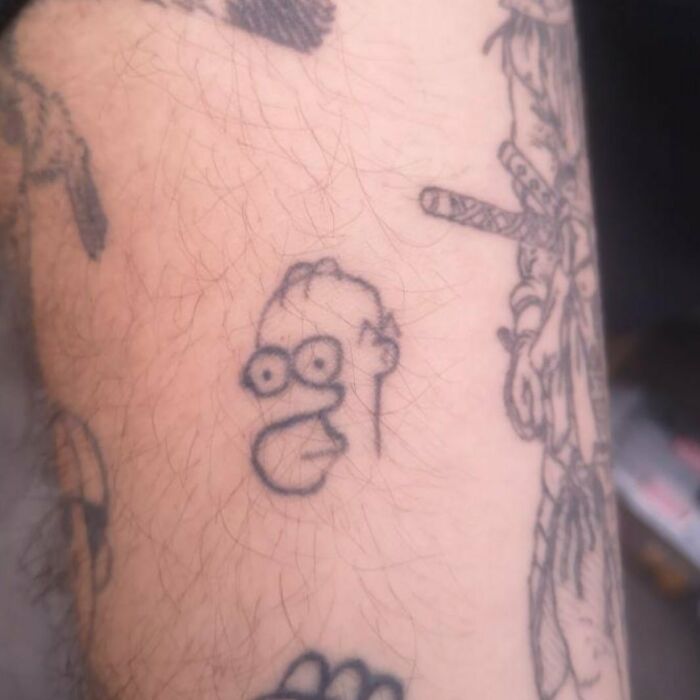 Minimalist cartoon character tattoo, showcasing sketchy line work on skin.