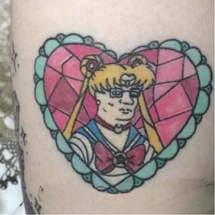 A quirky tattoo design featuring a humorous character within a colorful heart-shaped frame.