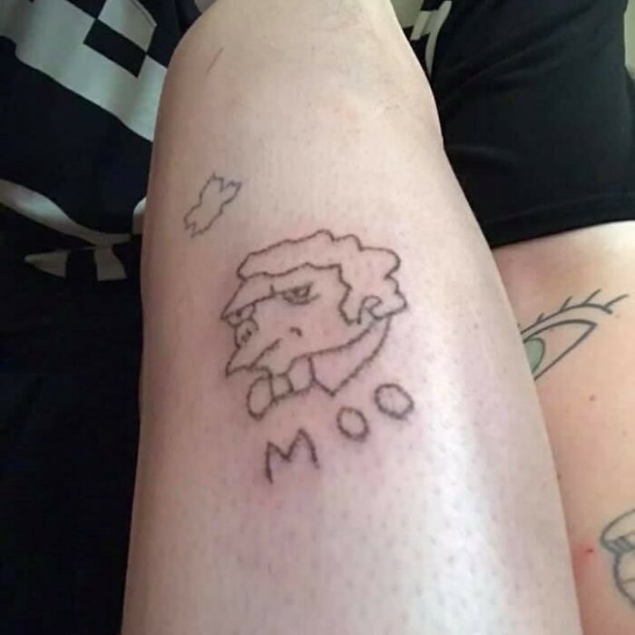 Minimalist Simpsons tattoo on forearm, featuring a simple sketch and the word "Moo."