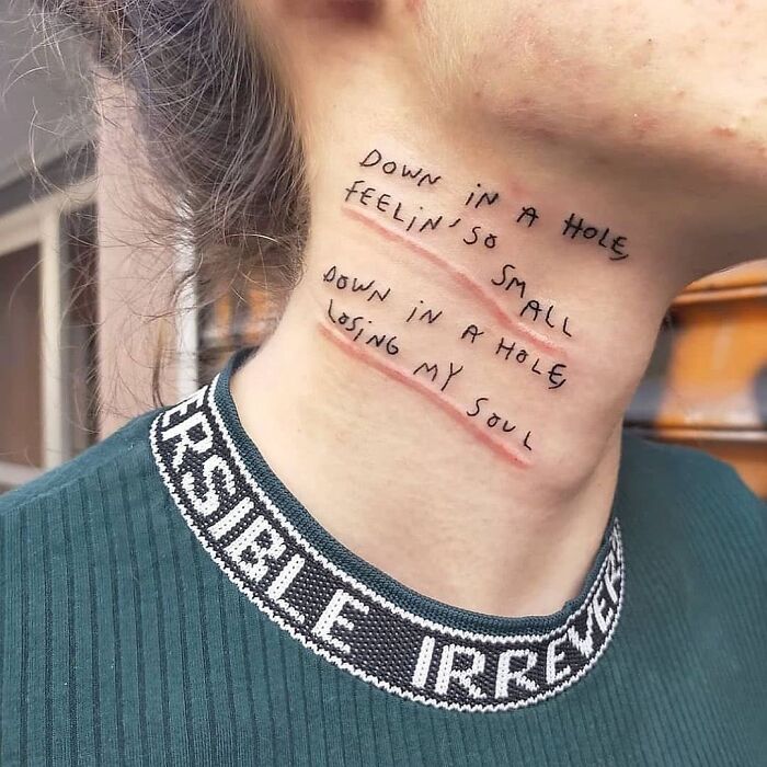 Neck tattoo with poorly spaced text featuring lyrics, with skin appearing irritated around the lines.