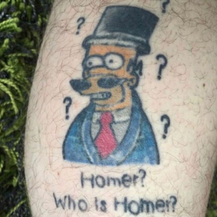 Simpsons tattoo of character in a suit with the text "Homer? Who is Homer?" surrounded by question marks.