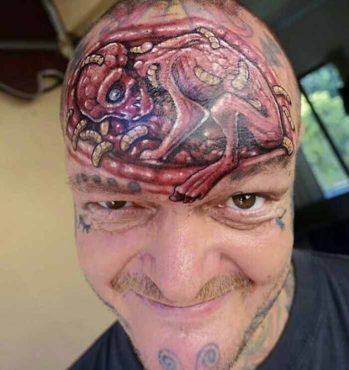 Man with unusual tattoo design on forehead, showcasing permanent ink mistake.