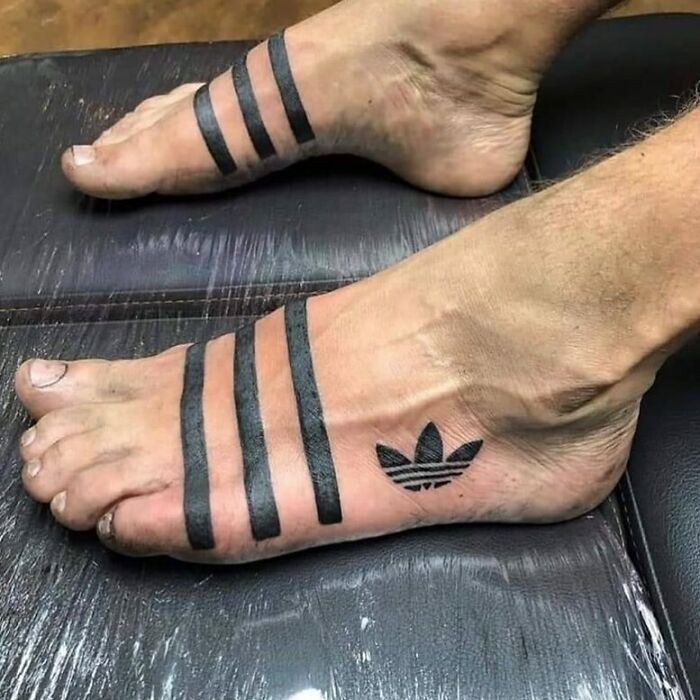 Tattoo mistakes featuring stripes and a logo inked on a person's feet.