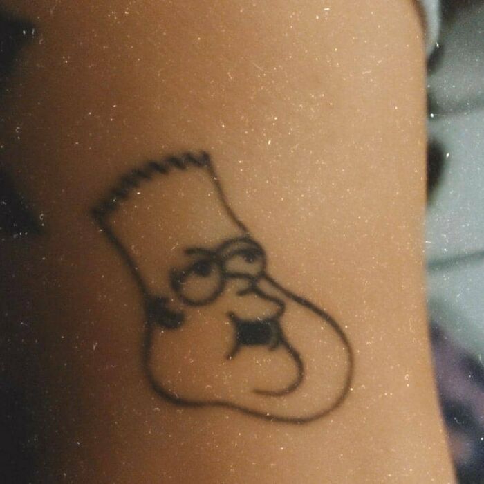 Cartoon character tattoo with distorted features on an arm, resembling a parody from The Simpsons series.
