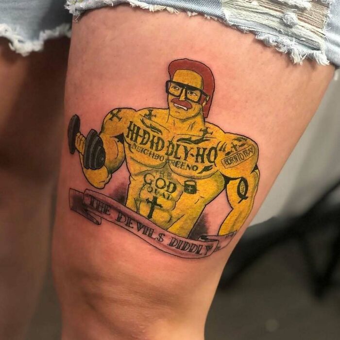 Muscular cartoon character tattoo on a thigh, featuring humorous elements from The Simpsons.