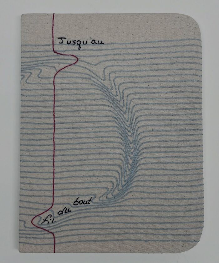 Fabric embroidered to resemble a notebook page with lines and French text.