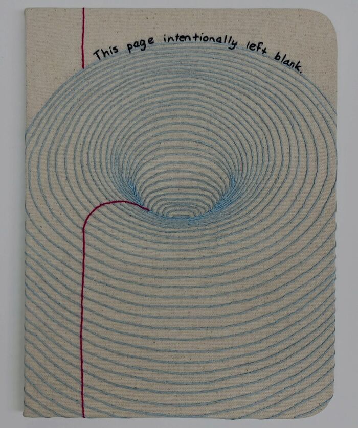 Fabric embroidered to resemble a notebook page with text "This page intentionally left blank."