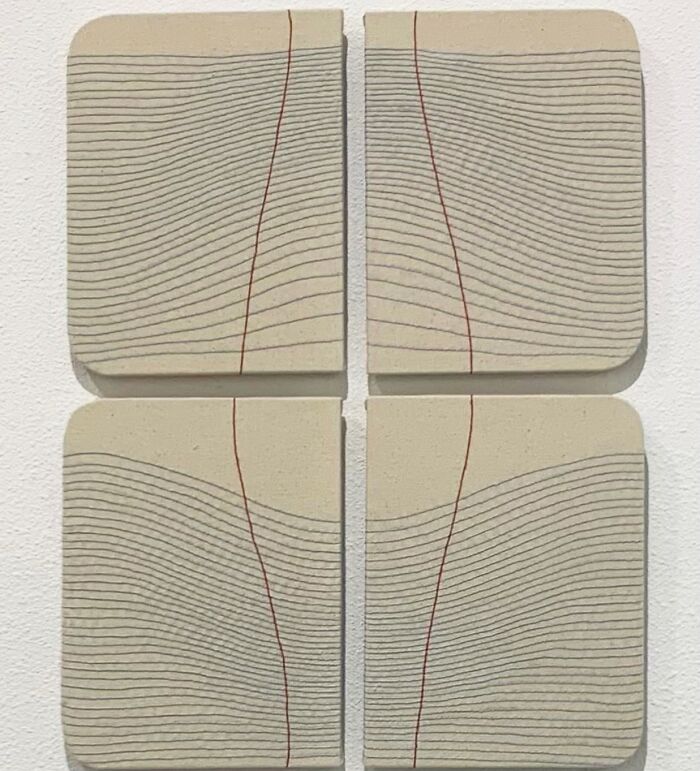 Embroidery art resembling notebook pages with wavy lines and red accents on fabric pieces.