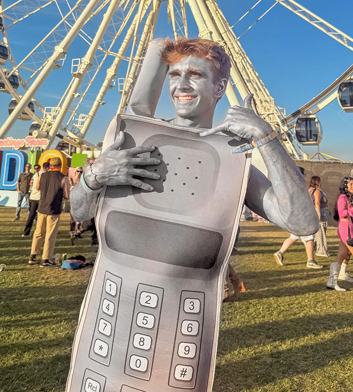 Man in silver body paint wearing a vintage cell phone costume at Coachella 2025, capturing worst dressed fashion.