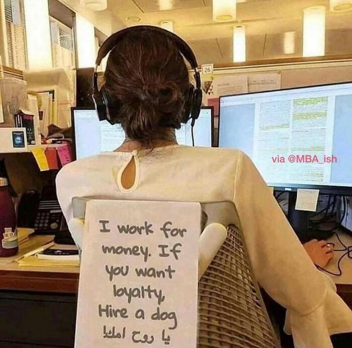 Office worker with headphones and a sign saying, "I work for money. If you want loyalty, hire a dog." Work meme humor.