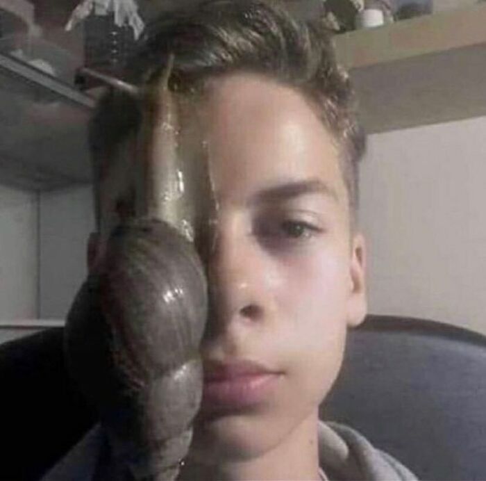 Teen with a large snail on his face, creating a surreal and random cursed image.