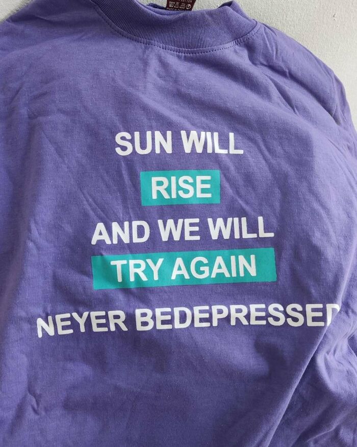 Purple T-shirt with funny translation: "Sun will rise and we will try again neyer bedepressed."