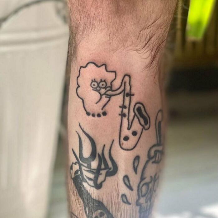 Simpsons tattoo featuring a rudimentary drawing of a character playing a saxophone on someone's arm.