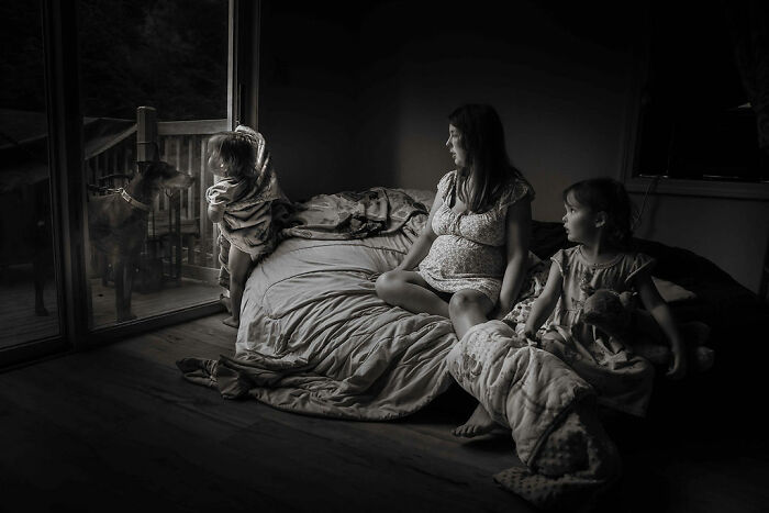 Family in a cozy rural Maine home, kids at the window with a dog, capturing intimate moments of rural life.