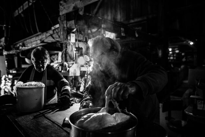 Two people in a rustic kitchen immersed in preparing food, capturing the essence of rural life in Maine.