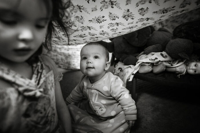 Two children in a cozy blanket fort surrounded by toys, capturing intimate rural life in Maine.