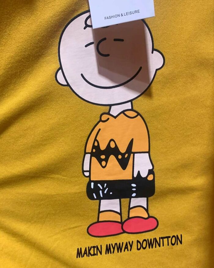 Yellow T-shirt featuring cartoon character with humorous typo, "Makin Myway Downtton," humorously lost in translation.