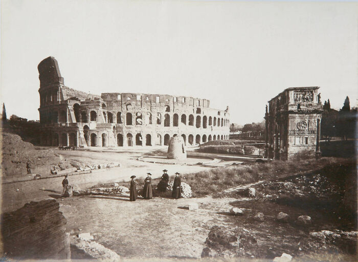 Black and white photo showing life in Europe 100 years ago with people near the Colosseum and ancient ruins in Rome.