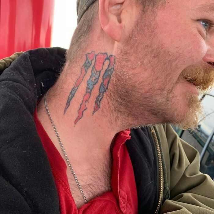 Man with claw tattoo on his neck, a common permanent mistake in tattoos, wearing a red shirt and jacket outdoors.