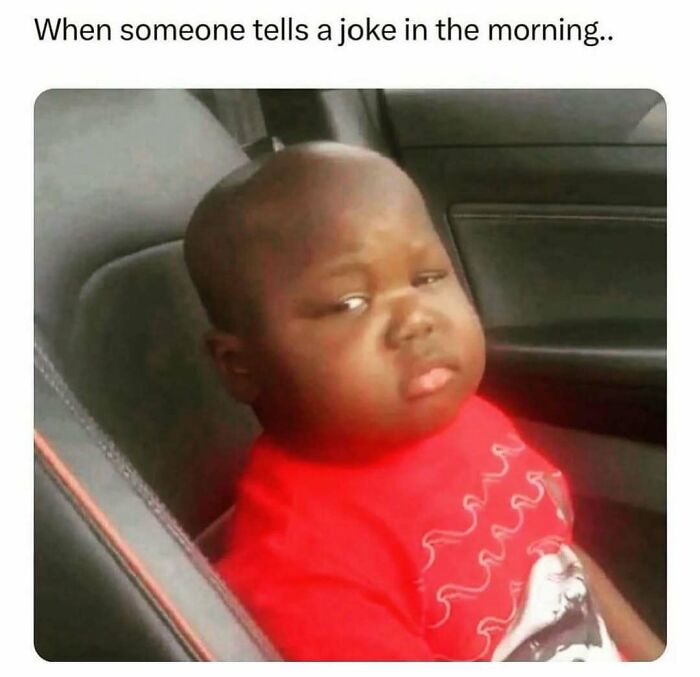 Child in a red shirt giving a skeptical look, capturing a relatable meme moment in a car seat.