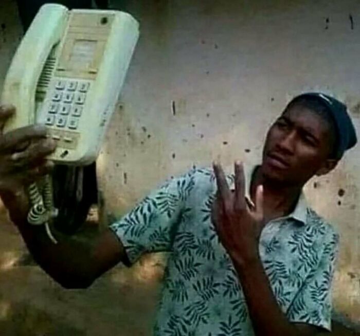 Person taking a selfie with a large vintage phone, capturing a humorous moment from an IG page.