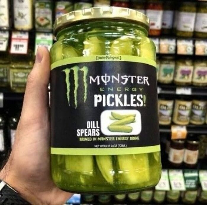 Jar of Monster Energy pickles held in a hand, displayed among other items on a grocery shelf.