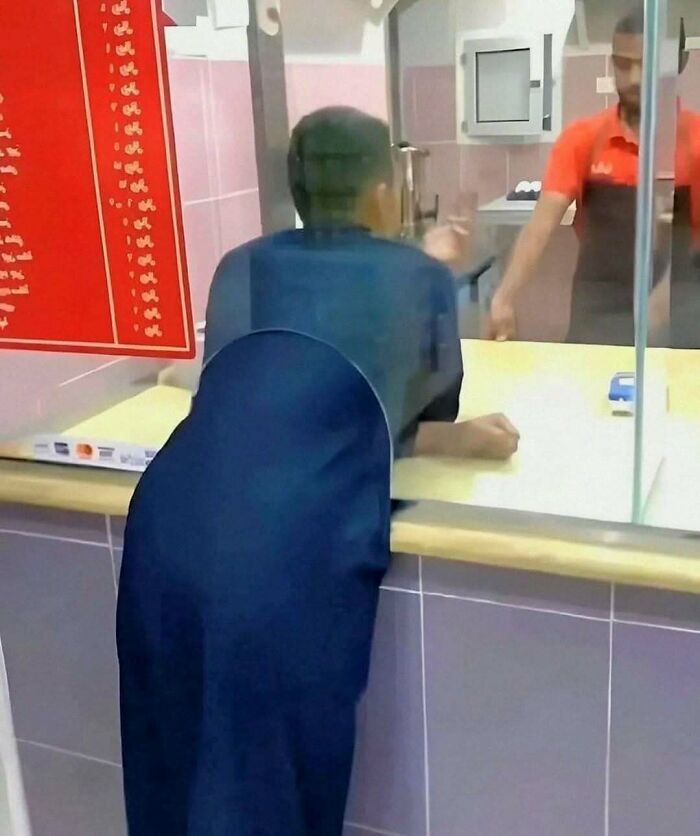 Person standing at a counter, speaking with a worker. Part of humorous content on a popular IG page featuring unique posts.