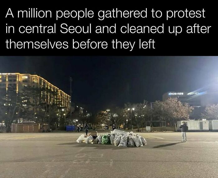 Clean protest aftermath in central Seoul with neatly piled garbage bags at night.