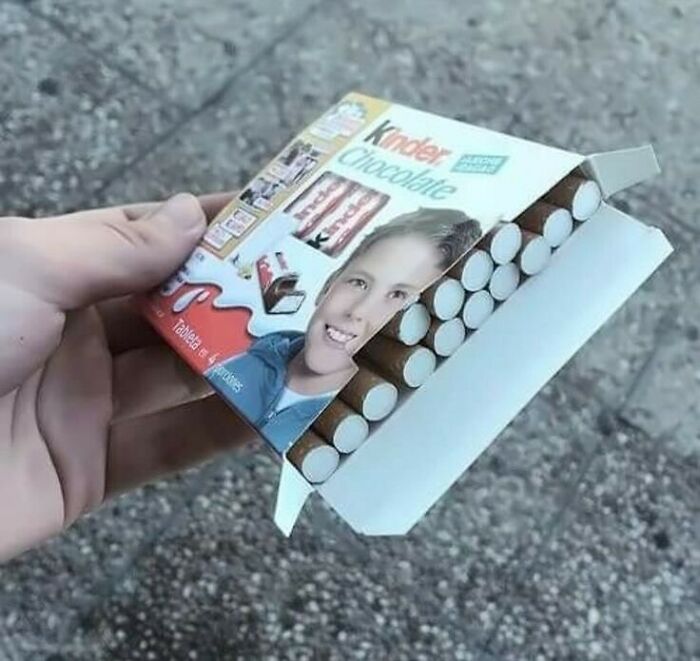 Hand holding a Kinder Chocolate box resembling a cigarette pack, showcasing a humorous visual twist.