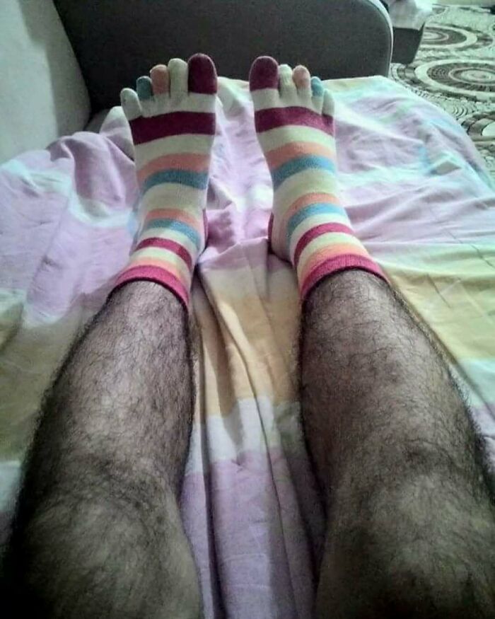 Colorful striped toe socks on legs, laying on a bed; best posts IG page feature.