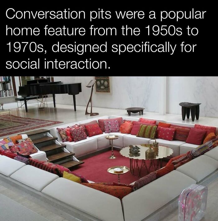 Mid-century conversation pit with colorful pillows and tables, designed for social interaction, featuring a piano in the background.