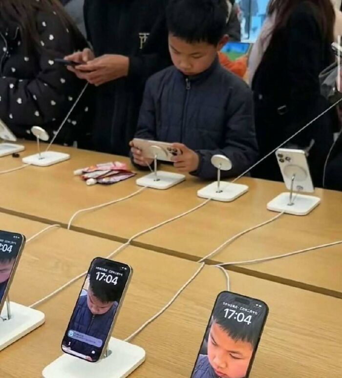 Cursed image of phones displaying a boy's face while he uses a device in a store.