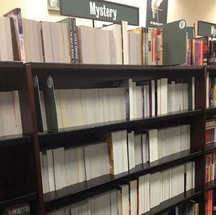 Books on a shelf with blank spines labeled "Mystery," creating a cursed visual effect.