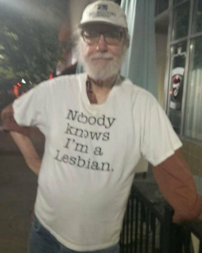 Man in a humorous shirt standing outside at night.