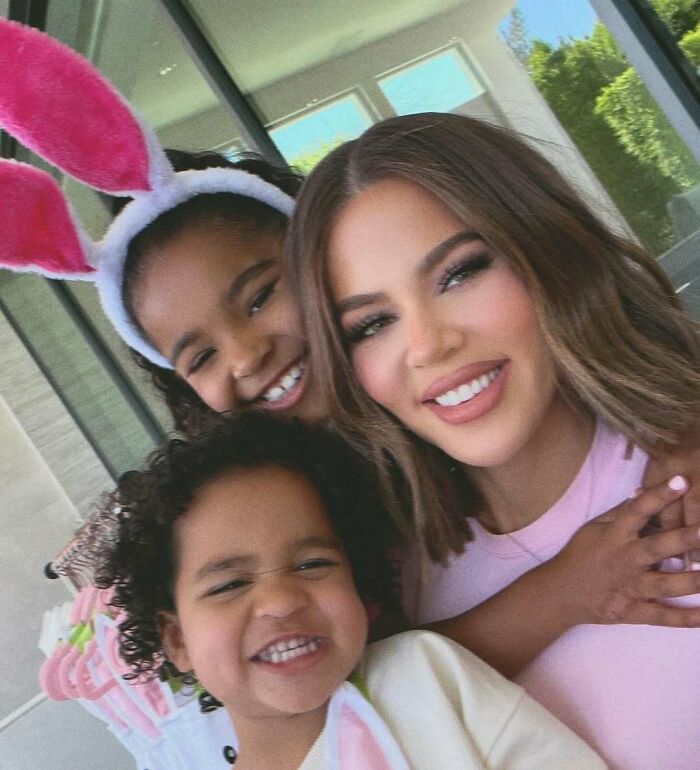 Woman smiling with two children wearing bunny ears, capturing a joyful celebrity encounter moment at home.
