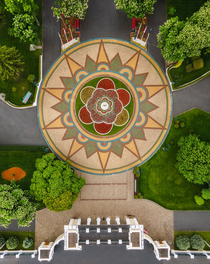 Aerial image of a geometric garden design surrounded by trees and pathways showcasing the world from above.
